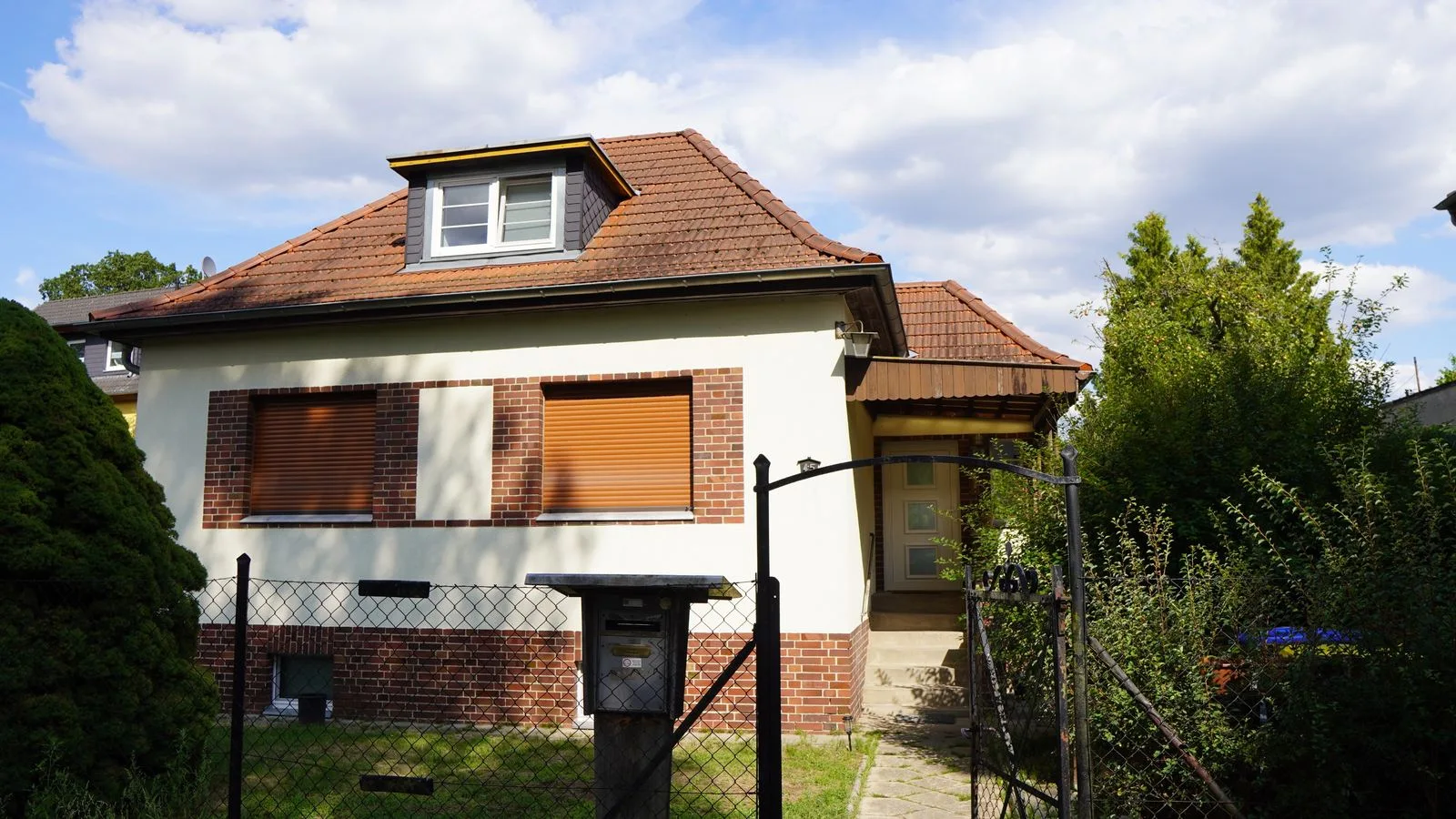 Haus Borgsdorf in Hohen Neuendorf: weißes Einfamilienhaus mit Ziegelsockel, rotem Dach und Gartentor